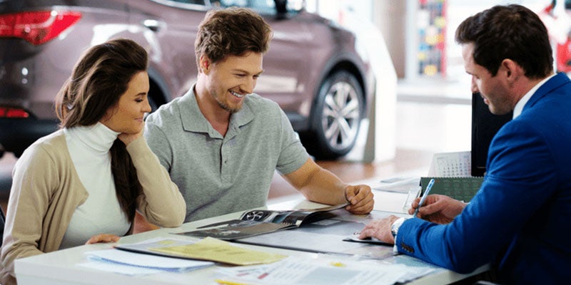 Smiling couple discussing financing process with dealer