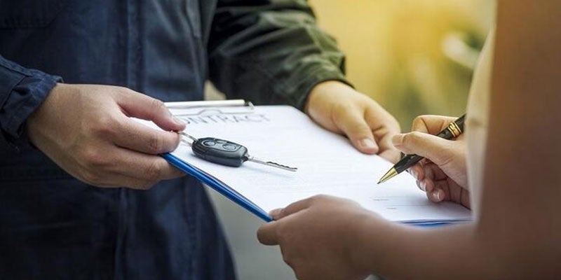 Vehicle owner being handed keys after signing leasing agreement